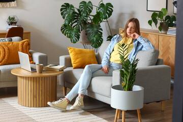 Wall Mural - Thoughtful teenage girl sitting on sofa at home