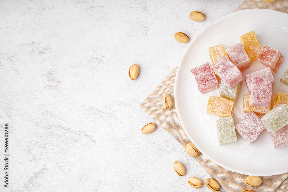 Plate with tasty Turkish Delight on light background