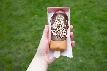 Festival Street Food Penis Shaped Waffle On Wooden Stick With Dark Chocolate, Decorated With White Air Corn Balls In Paper Box In Human Hand Outdoor. Sweet Cookie Horizontal Plane