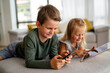 © NDABCREATIVITY - Little girl and boy watching video or playing games on their digital device tablet, smartphone.