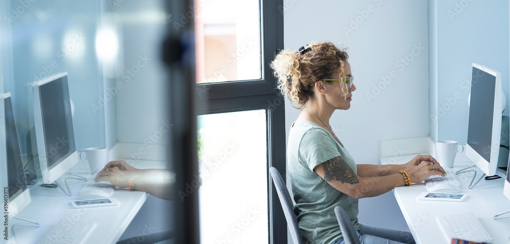 One young modern woman working on computer sitting at the desk in ...