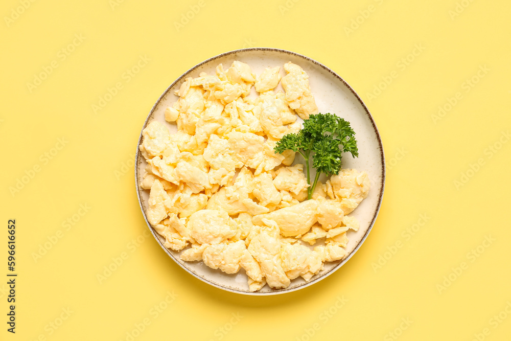 Plate of yummy scrambled eggs on yellow background