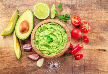 Canvas Print - Guacamole, guacamole ingredients and chips on wooden background.  Flat lay.