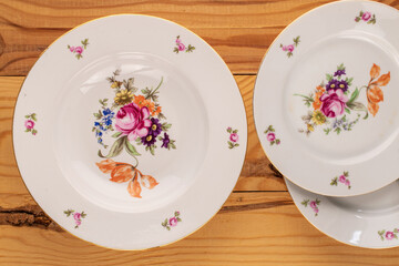 Canvas Print - Three old porcelain plates on a wooden table, macro, top view.