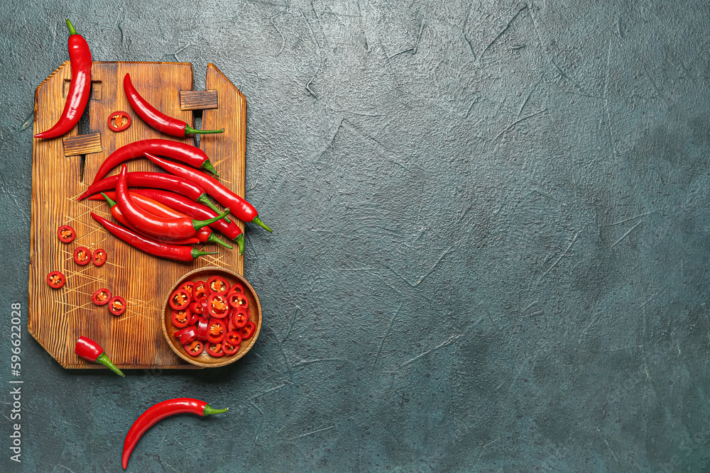 Wooden board with fresh chili peppers on dark background