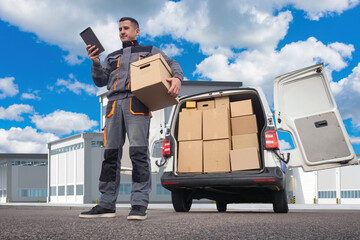 Wall Mural - Deliveryman. Man courier with tablet. Employee of logistics company near minivan. Courier under blue sky. Man works in delivery service. Transport company agent. Courier on territory of enterprise