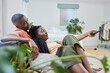 © Oostendorp/peopleimages.com - Young african american couple changing channels on remote and watching television together on sofa at home. Girlfriend relaxing on boyfriends lap while enjoying entertainment shows, series and movies