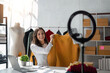 © Natee Meepian - Young lady fashion designer using mobile phone showing clothes recording video live streaming online at shop. Small business owner, online market delivery concept