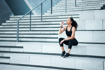 Poster - Taking in some liquids. Full length shot of an attractive young female athlete exercising outside in the city.