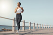 © Nicholas Felix/peopleimages.com - Full length of fit young female athlete in sportswear wearing wireless headphones and listening to music while out for a run along the promenade. Exercise is good for you health and wellbeing