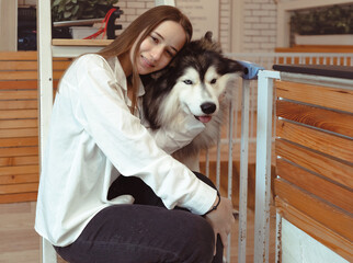 Young woman and her dog carefree at home background. Beautiful girl have fun playing with her adorable pet friend at leisure. Friendly malamute happy cuddle and sleep with owner who love and care.