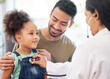 © Talia M/peopleimages.com - Shes very healthy, dad. Shot of a little girl sitting on her fathers lap while being examined by her doctor.