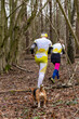 Young couple wearing sportswear and a dog running through a forest