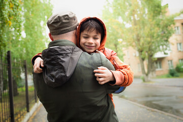 Wall Mural - Military man in olive uniform and cap hugging his little son after long parting