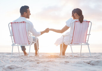 Poster - Distance will never decrease my love for you. Shot of a young couple holding hands while sitting on their beach chairs.