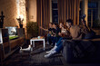 © master1305 - Group of friends, sport fans sitting on couch at home in the evening and emotionally watching online football match. Concept of friendship, leisure activity, weekends, fun, emotions