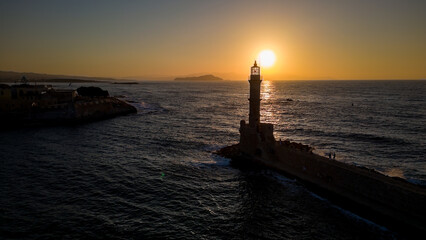 Wall Mural - Sunset behind an old stone lighthouse in the Greek town of Chania, Crete