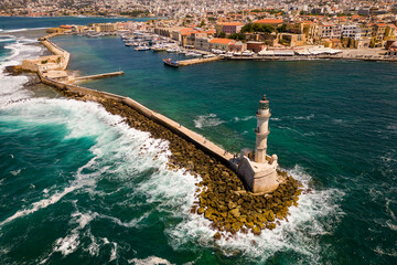 Wall Mural - Aerial view of a lighthouse and breakwater protecting a harbor from a rough sea (Chania, Crete, Greece)