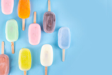 Wall Mural - Selection of multicolored ice cream popsicles. Various flavor gelato, frozen lollypops - chocolate vanilla blueberry strawberry pistachio orange, on light blue background