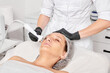 © TRAVELARIUM - Cosmetologist makes ultrasound skin tightening for rejuvenation woman face using phonophoresis, anti aging cosmetic procedure with in beauty spa salon. Beautician makes ultrasonic skincare lifting