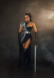 Portrait fantasy african american woman warrior holding sword weapon in hand. Dark queen girl black military dress costume. Gothic lady elf fairy. Sexy beauty face fashion model pposing. Studio photo