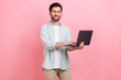 © deagreez - Photo portrait of handsome young guy hold laptop typing coder working dressed stylish blue clothes isolated on pink color background