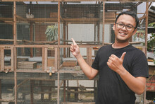 Handsome Asian Man Is Smiling And Standing In Front Of Bird Cage