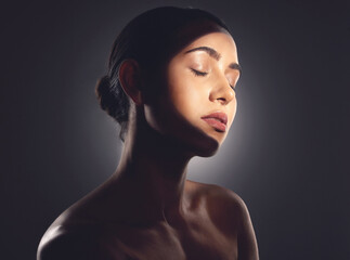 Wall Mural - Beauty is the light in the heart. Studio shot of a beautiful young woman posing with light beam against her face.