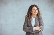 © Dragana Gordic - Confident young woman standing with folded arms on gray wall. Portrait of smiling businesswoman with arms crossed isolated against grey background with copy space.