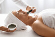 Beauty Treatments. Cosmetologist applying clay mask to middle aged woman at spa