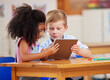 © Nina L/peopleimages.com - Learning with a little help in the classroom. Shot of two preschool students looking at something on a digital tablet together.