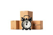 © wabeno - Black alarm clock and cardboard boxes on white background -Concept fast shipping, storage time in the warehouse, delayed delivery