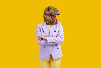 Strict extravagant business lady in funny disguise. Confident woman wearing cool lilac jacket and ugly freaky bizarre dinosaur mask standing with her arms crossed isolated on yellow colour background