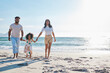 © Nina L/peopleimages.com - A walk in the sunshine. Full length shot of an affectionate young family of three taking a walk on the beach.