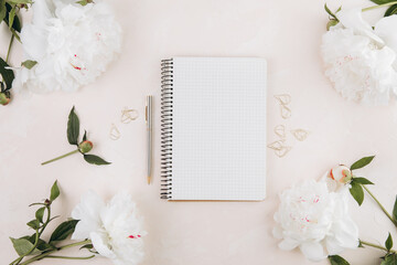 Feminine workspace with blank open notepad and peony flowers, stylish office writing supplies and on a pastel teble