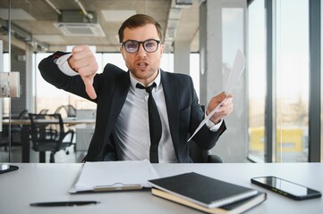 Wall Mural - Angry senior businessman sitting at his desk and screaming