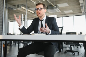 Wall Mural - Angry businessman sitting at his desk and screaming at his employees.