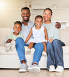 © Irshaad Majal/peopleimages.com - Portrait of a happy african american family with two children sitting on the couch at home. Adorable little girl and boy sitting with their mom and dad. Affectionate family of four bonding at home