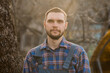 © Andrey - A farmer man of European appearance rural portrait in sunlight with a beard, a shirt and overalls looks at the camera outdoor