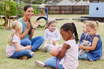 we learn, play and love. shot of a teacher spending time outside with preschool children.