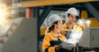 © Montri - two professional engineer,worker,technician use clipboard discuss work, walk in steel metal manufacture factory plant industry. Black African American man and woman wear hard hat check quality machine
