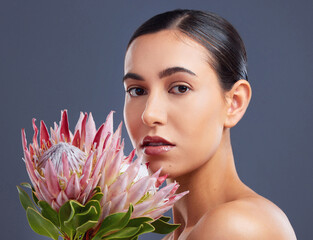 Wall Mural - Turn to nature for all things wonderful. Studio shot of a beautiful young woman posing with proteas against a grey background.