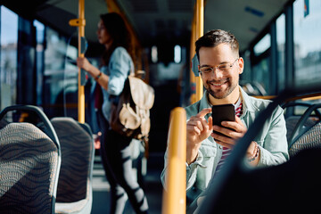 Happy man text messaging on cell phone in bus.