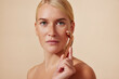 © Artem Varnitsin - Young woman with smooth skin using a facial roller. Blond female doing skincare routine.