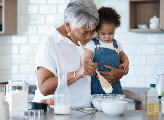 Wall Mural - This is how we make your favourite treat. Shot of a senior woman baking with her granddaughter at home.