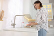 © New Africa - Happy young woman washing plate above sink in modern kitchen