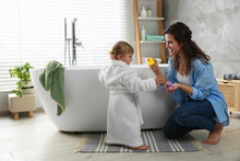 Mother Playing With Her Daughter Near Tub In Bathroom