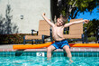 Oudoor summer activity. Concept of fun, health and vacation. Boy eight years old sits near a pool in hot summer day.