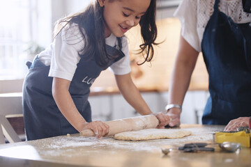 Sticker - Baking sure is fun. Shot of an adorable little girl rolling out dough.