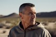 © Eber Braun - Photography in the style of pensive portraiture of a satisfied man in his 40s wearing a comfortable tracksuit against a desert background. Generative AI